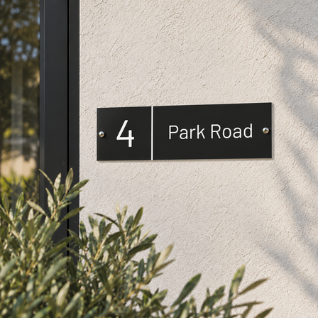 Black aluminium house name plate reading 4 Park Road screwed flush to a rendered house facade